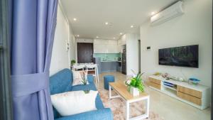 uma sala de estar com um sofá azul e uma mesa em Luna's House - Vinhomes D'Capitale - 2Br Apt em Hanói