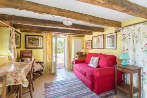 ein Wohnzimmer mit einem roten Sofa und einem Tisch in der Unterkunft Maison Le Bois Béni in Siorac-en-Périgord