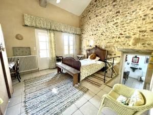 ein Schlafzimmer mit einem Bett und einer Steinmauer in der Unterkunft Maison Le Bois Béni in Siorac-en-Périgord