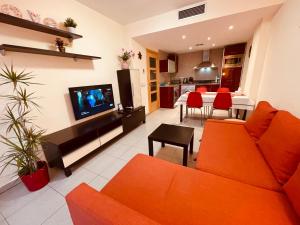 a living room with orange furniture and a kitchen at Relax LUX apartment on Fenals beach in Lloret de Mar