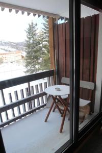 a balcony with a table and a chair and a window at Appartement aux pieds des pistes chez Seb et Isa in Saint-François-Longchamp