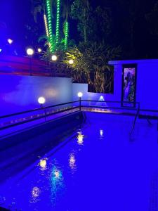 Arabian Holiday Resort Family Cottage One Room Two Bed في ادوكي: حمام سباحة في الليل مع أضواء زرقاء وأخضر