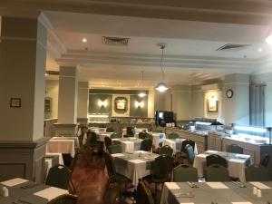 un comedor con mesas y sillas blancas y una habitación con mesas y sillas en Windsor Hotel, en Sliema