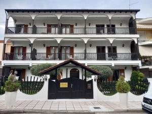 - un bâtiment blanc avec une porte noire et un balcon dans l'établissement Amaryllis House, à Platamonas