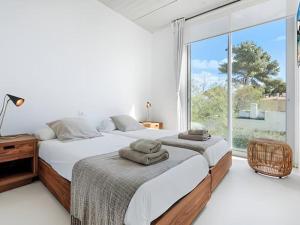 2 bedden in een slaapkamer met een groot raam bij Villa Cuc in Playa de Muro
