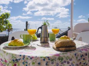 a table with a table cloth with bread and glasses of orange juice at Casa Bella Vista frente al mar y piscina natural. in Charco del Palo