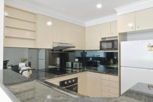 uma cozinha com armários brancos e bancadas pretas em Great Location! Darling Harbour Superb 2BR Apt em Sidney