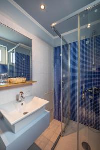 a bathroom with a sink and a glass shower at Kitro Beach Hotel - Adults Only in Agios Nikolaos