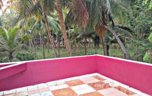 een roze kamer met palmbomen op de achtergrond bij Reves by Le Apex in Kottakupam
