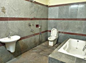 een badkamer met een wastafel, een toilet en een bad bij Reves by Le Apex in Kottakupam