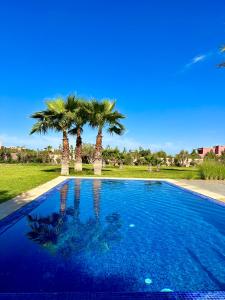 une piscine bleue avec des palmiers en arrière-plan dans l'établissement Mandar Atlas, à Marrakech
