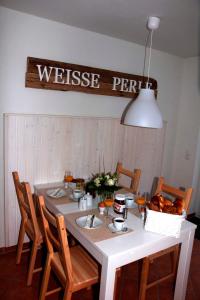 ペルツァーハケンにあるPommerening Veraの白いテーブル(椅子付)、壁にウェルカムサイン