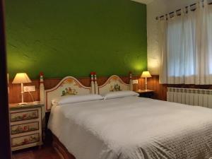 a bedroom with a white bed with a green wall at Casa Rural Crisol Spa in Arenas de San Pedro