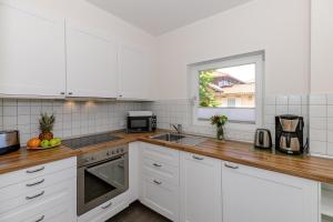 a kitchen with white cabinets and a sink and a window at Apartmenthaus Strandstraße 34 in Kühlungsborn