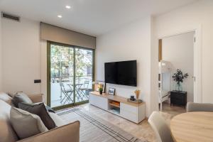 un soggiorno con divano e TV a parete di Cozy Apartment Les Corts a Barcellona