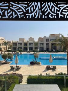 una piscina con sillas y sombrillas frente a un edificio en Mangroovy Residence El Gouna - Grovin en Hurghada