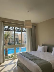 a bedroom with a large bed and a large window at Mangroovy Residence El Gouna - Grovin in Hurghada
