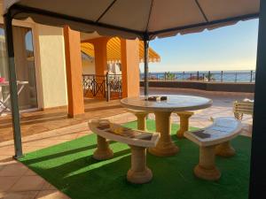 un patio con una mesa y 2 bancos sobre una alfombra verde en Villa Tenerife Sur, en Los Cristianos