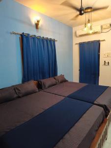 um quarto com uma cama grande e cortinas azuis em Omkara - The Fives Guest house em Tiruvannamalai