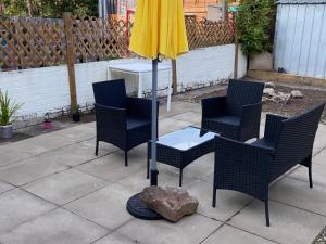 Private Lounge and Double Room في Kilwinning: مجموعة من الكراسي ومظلة على الفناء