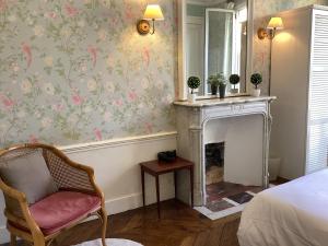 a bedroom with a fireplace and a chair and wallpaper at BED and BREAKFAST PARIS QUARTIER CHAMPS-ÉLYSÉES in Paris
