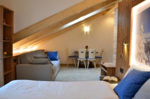 1 dormitorio con cama, sofá y mesa en Aria Alpina Guest House Affittacamere, en Predazzo