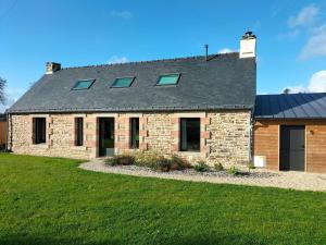 a stone house with a gray roof and a yard at le jardin Médicis avec spa et sauna in Trédion