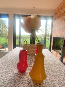 zwei Vasen auf einem Tisch mit einer Rose in der Unterkunft B&B NR6 in Herbaijum