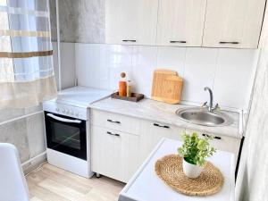 eine kleine Küche mit weißen Schränken und einem Waschbecken in der Unterkunft Уютная однушка в центре города in Temirtaū