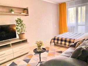 ein Wohnzimmer mit einem Sofa und einem TV in der Unterkunft Уютная однушка в центре города in Temirtaū