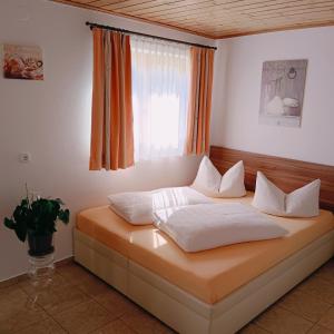 a bed with white pillows in a room with a window at Apartments Egger Barbara in Gosau