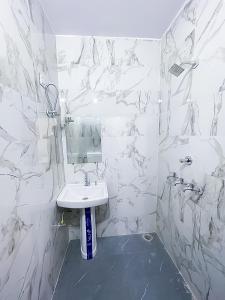 ein weißes Badezimmer mit einem Waschbecken und einem Spiegel in der Unterkunft Hotel In North Campus in Neu-Delhi