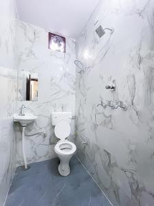 ein weißes Bad mit einem WC und einem Waschbecken in der Unterkunft Hotel In North Campus in Neu-Delhi