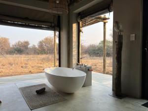 a large white bath tub in a room with a window at LookOut Safari Lodge in Klipdrift