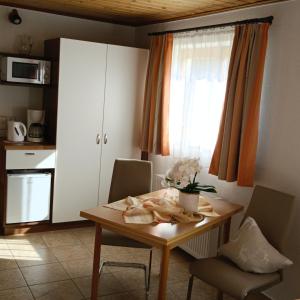 eine Küche mit einem Holztisch mit Stühlen und einem Fenster in der Unterkunft Apartments Egger Barbara in Gosau