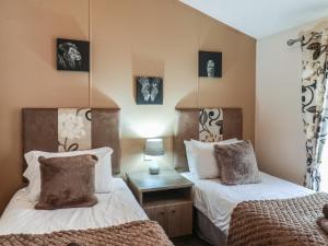 a bedroom with two beds and a table with a lamp at Evergreen Pines in Scarborough