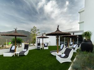 un groupe de chaises et de parasols sur une pelouse dans l'établissement Hotel Altos de Istán, à Istán