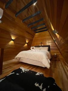 a bedroom with a large bed with a wooden ceiling at Chalés Vista dei Monti 