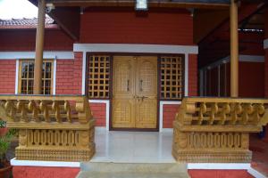 a house with a wooden door and two benches at Panchavati Home Stay in Sringeri