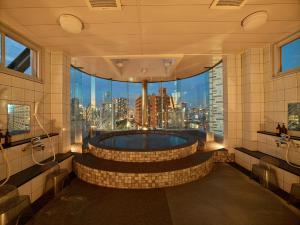a bathroom with a tub with a view of the city at Hotel Sunplaza in Osaka