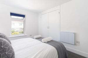 a white bedroom with a large bed and a window at Bright and Modern St Just 1 bedroom apartment in old Cornwall in St. Just