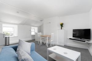a living room with a blue couch and a table at Bright and Modern St Just 1 bedroom apartment in old Cornwall in St Just