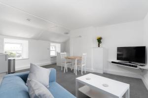 a living room with a blue couch and a table at Bright and Modern St Just 1 bedroom apartment in old Cornwall in St. Just