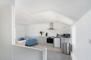 a kitchen with white cabinets and a blue couch at Bright and Modern St Just 1 bedroom apartment in old Cornwall in St Just