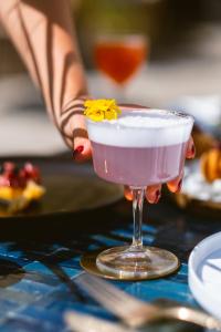 a person holding a pink drink with a yellow flower in it at The Vista Rooms & Terrace in Rome