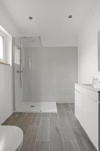 a white bathroom with a shower and a toilet at Sunny Apt in Almada with Tejo View in Almada