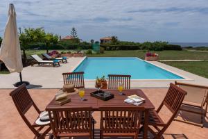 a wooden table with chairs next to a swimming pool at Aleli Villas with Tennis Court in Minia