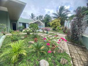um jardim em frente a uma casa com flores cor-de-rosa em Lucia’s Place em Tanauan