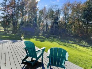 two green chairs sitting on a wooden deck at Robinson Cabin cabin in Warren