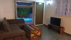 Una sala de estar con un sofá y un televisor de pantalla plana. en Villa Zeinga, en Sainte-Anne